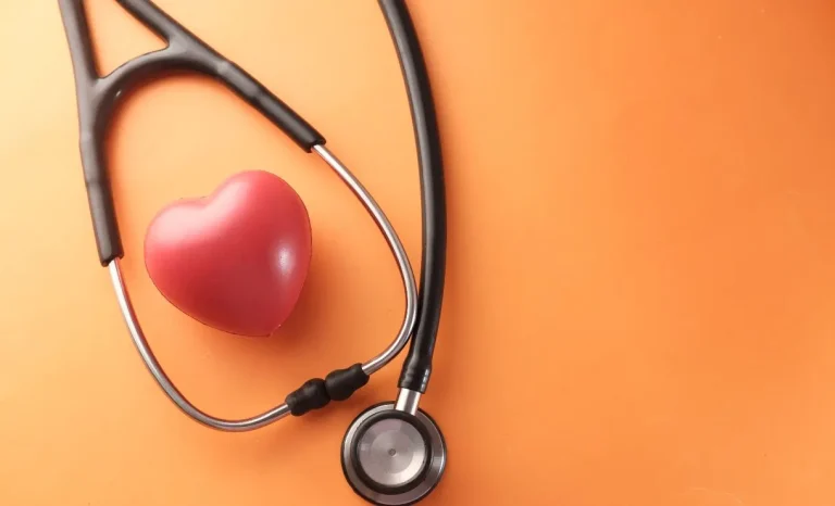 Coração vermelho ao lado de estetoscópio simbolizando saúde cardiovascular